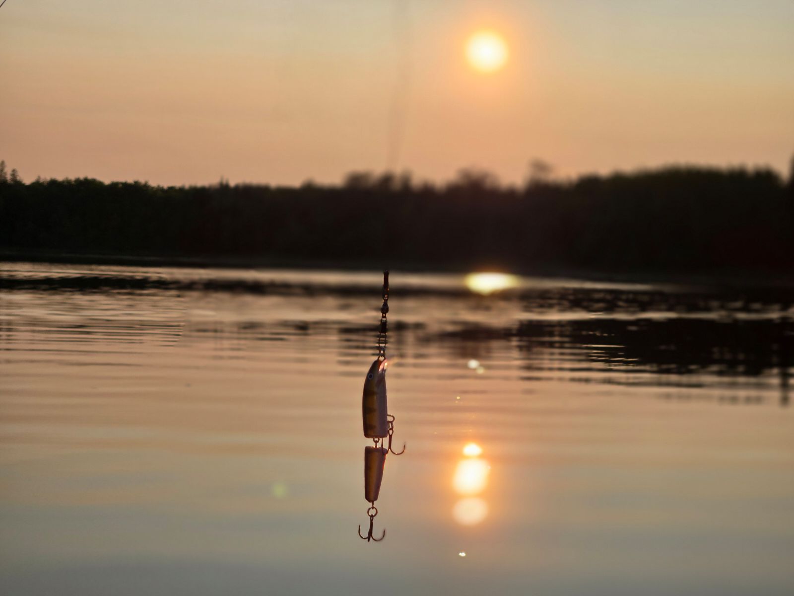 Minnesota fishing lure dangling over a lake at sunset